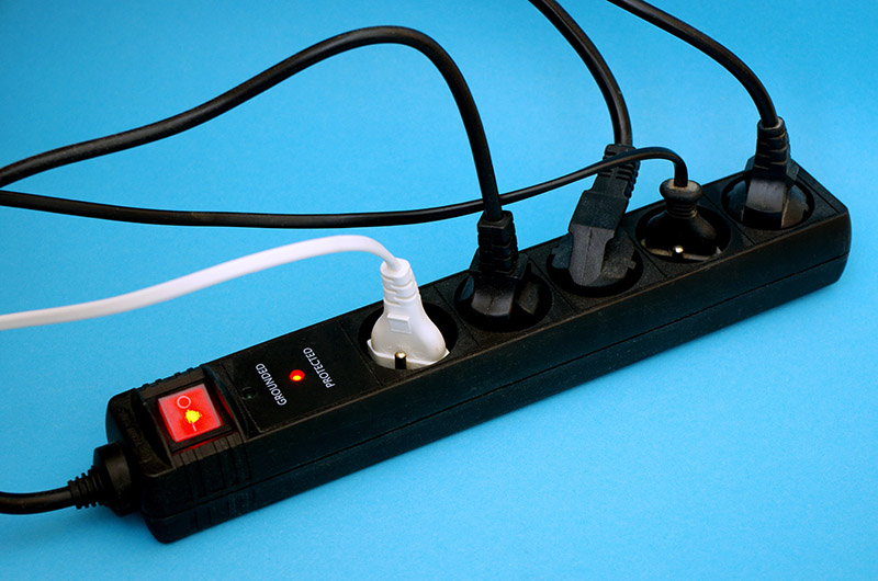 Cables plugged into black power strip with surge protection